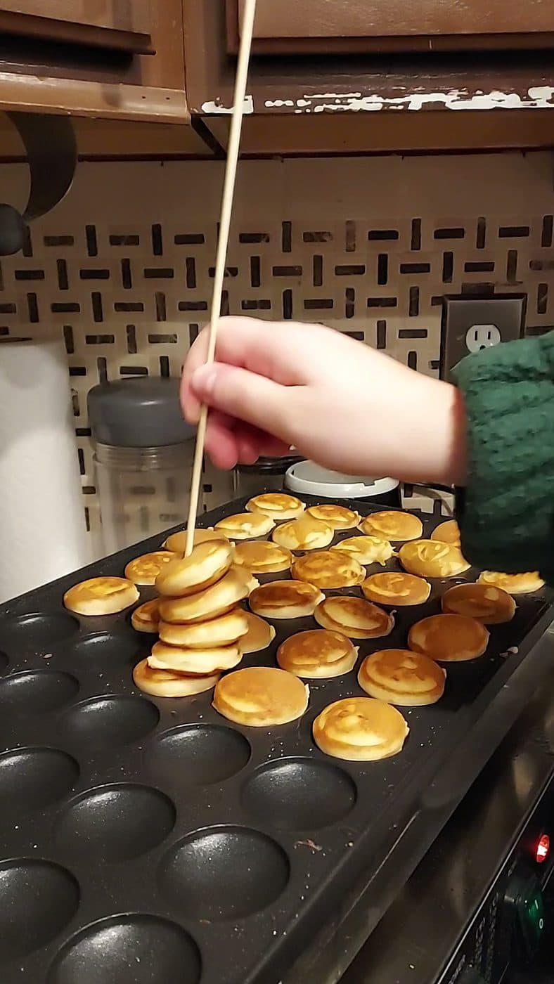 Turning Dutch mini pancakes with a skewer on the poffertjes griddle at a Cincinnati event